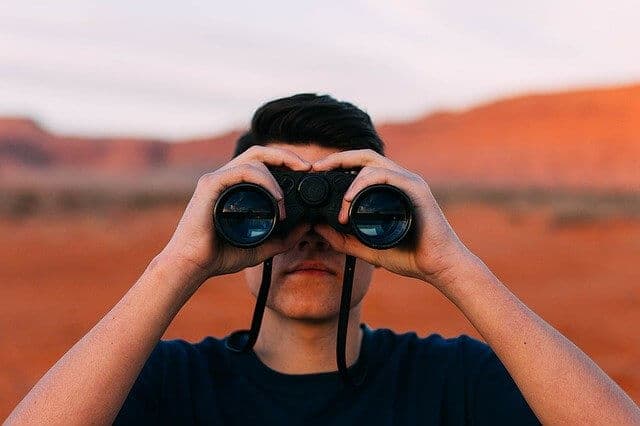 Man looking in black binoculars