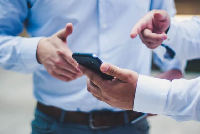 A Person in a Blue Shirt Pointing at Smartphone